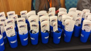 Image of several blue cups with the VAIL logo and with VAIL brochures inside of them.